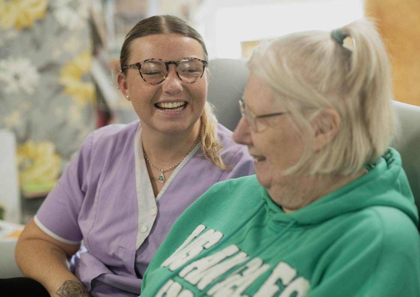 Pflegekraft und Seniorin lachen gemeinsam